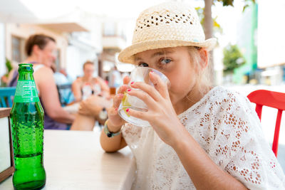 Portrait of girl drinking glass on table