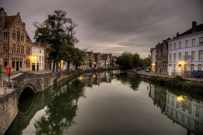 Canal amidst buildings in city against sky at dusk