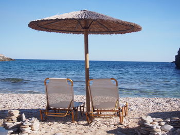 Deck chairs on beach against clear sky