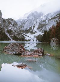 Scenic view of lake by snowcapped mountains against sky