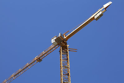 Low angle view of crane against clear blue sky