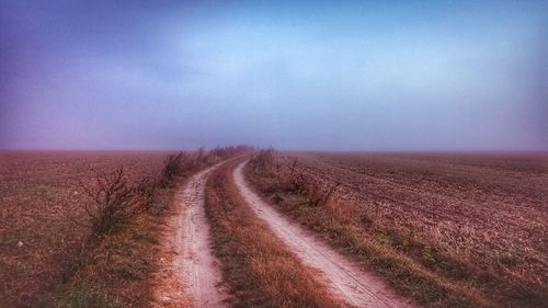 Road amidst field against sky