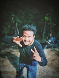 Portrait of boy holding camera while standing outdoors