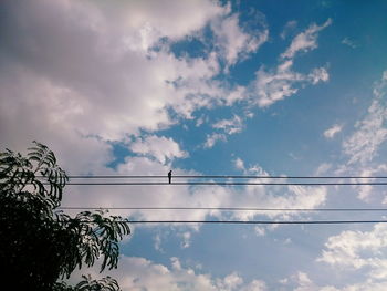 Low angle view of power cables against cloudy sky