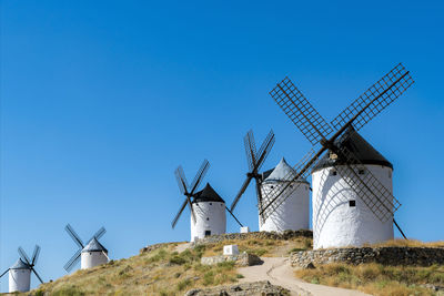 Traditional windmills on land against clear blue sky