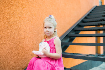 Portrait of cute girl standing against wall