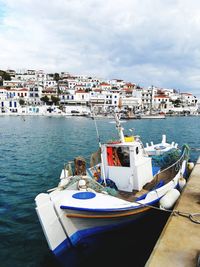 Sailboats moored in sea against buildings in city