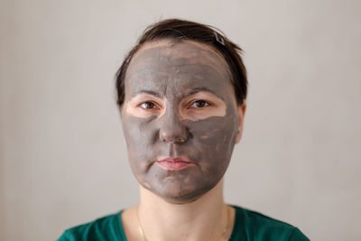 Portrait of mid adult woman with facial mask standing against wall