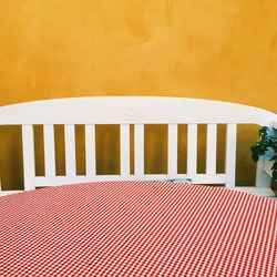 High angle view of empty seat and table by yellow wall at cafe