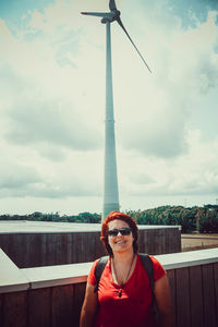 Portrait of smiling young woman standing against sky