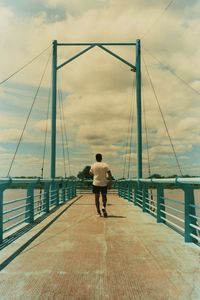 Rear view of man on bridge against sky