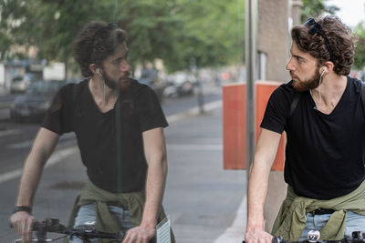 Young man riding bicycle looking at window