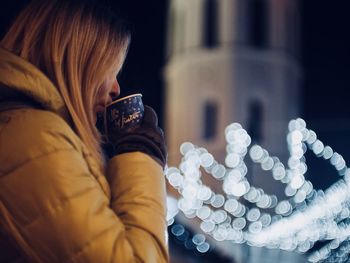 Close-up of woman drinking coffee in city during night