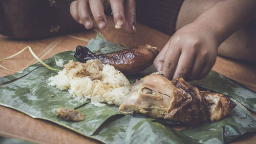 Close-up of hand holding meat in plate