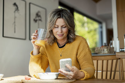 Smiling woman at table using cell phone
