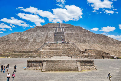 Tourists at historical building against cloudy sky