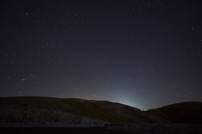 Low angle view of hill against star field sky during night