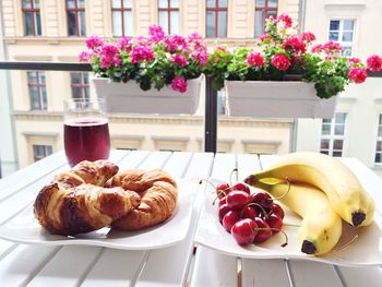 Close-up of fruits with bread and drink served on table at home