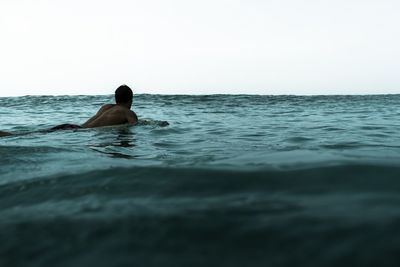 Man swimming in sea against sky
