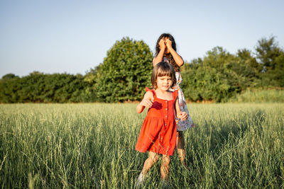 Two girls in dresses playing in the evening field