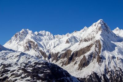 Scenic view of snow covered mountains against blue sky