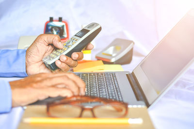 Midsection of man using laptop on table