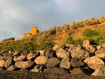 Stone wall by rocks against sky