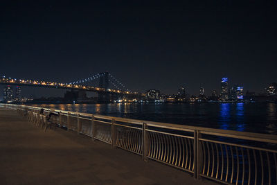 Illuminated bridge over river against sky at night