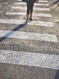 Low section of woman walking on zebra crossing