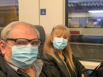 Portrait of senior couple wearing mask sitting in train