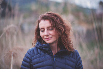 Smiling woman with closed eyes standing outdoors