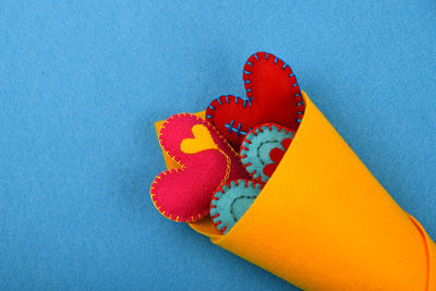 Colorful heart shapes art in yellow rolled paper on blue background