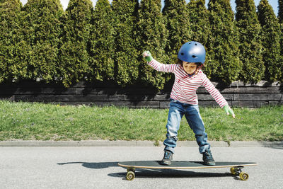 Full length of boy balancing on skateboard at yard