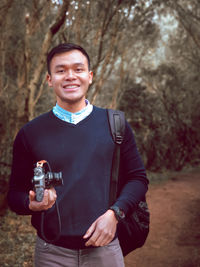 Young man holding camera with big smile on his face