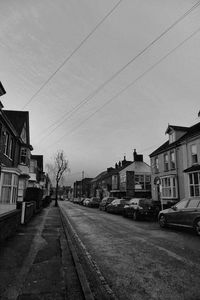 Road by buildings in city against sky