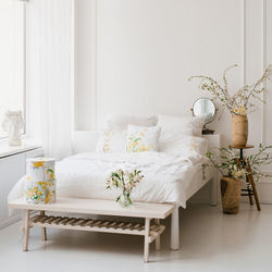 White bedroom interior with windows, spring accessories and white sheets on a king-size bed