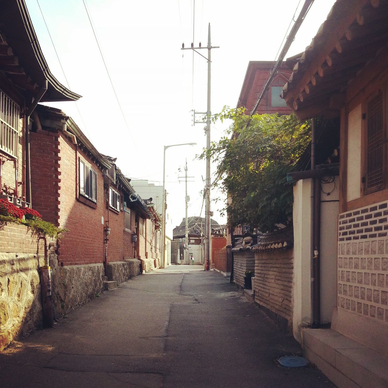 building exterior, architecture, built structure, the way forward, residential structure, residential building, street, house, power line, clear sky, diminishing perspective, building, city, narrow, alley, cable, town, electricity pylon, road, day