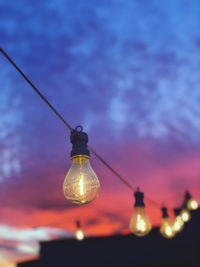 Low angle view of illuminated light bulb against sky