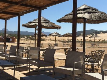 Thatched roof parasols and chairs arranged at sandy beach