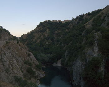 Scenic view of river by mountains against clear sky