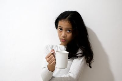 Portrait of a woman drinking drink against wall