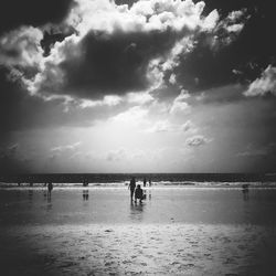 View of calm beach against cloudy sky