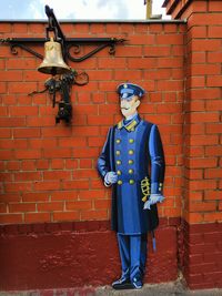 Full length of man standing against brick wall