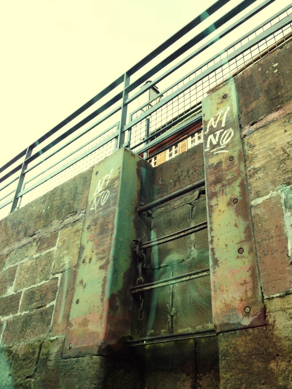 architecture, built structure, building exterior, low angle view, communication, text, western script, guidance, clear sky, day, wall - building feature, information sign, brick wall, no people, outdoors, metal, building, sign, sky, information