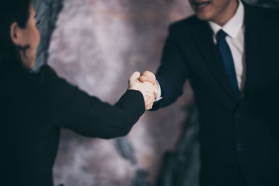 Midsection of business coworkers shaking hands in office