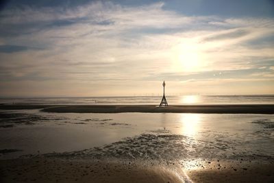 Silhouette people on beach against sky during sunset