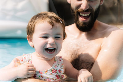 Selective focus on the face of a girl that is laughing in the water embracing a man