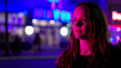 Portrait of young woman looking away at night