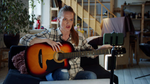 Woman playing guitar while learning online