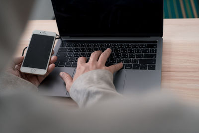 Midsection of person using laptop on table